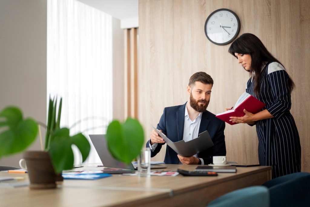 Business professionals reviewing documents and discussing employee benefits plan and payroll savings strategies in an office