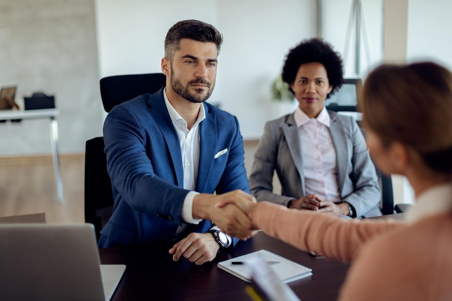 Business professionals shaking hands after discussing employee benefits plan, payroll savings, and financial consultation services